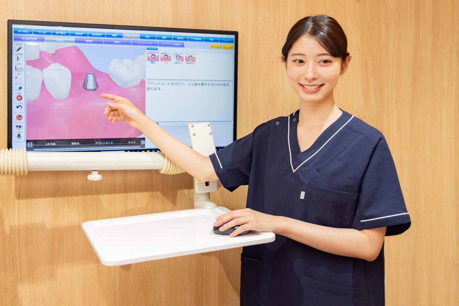 モニターのインプラント画像を指して説明する歯科スタッフ