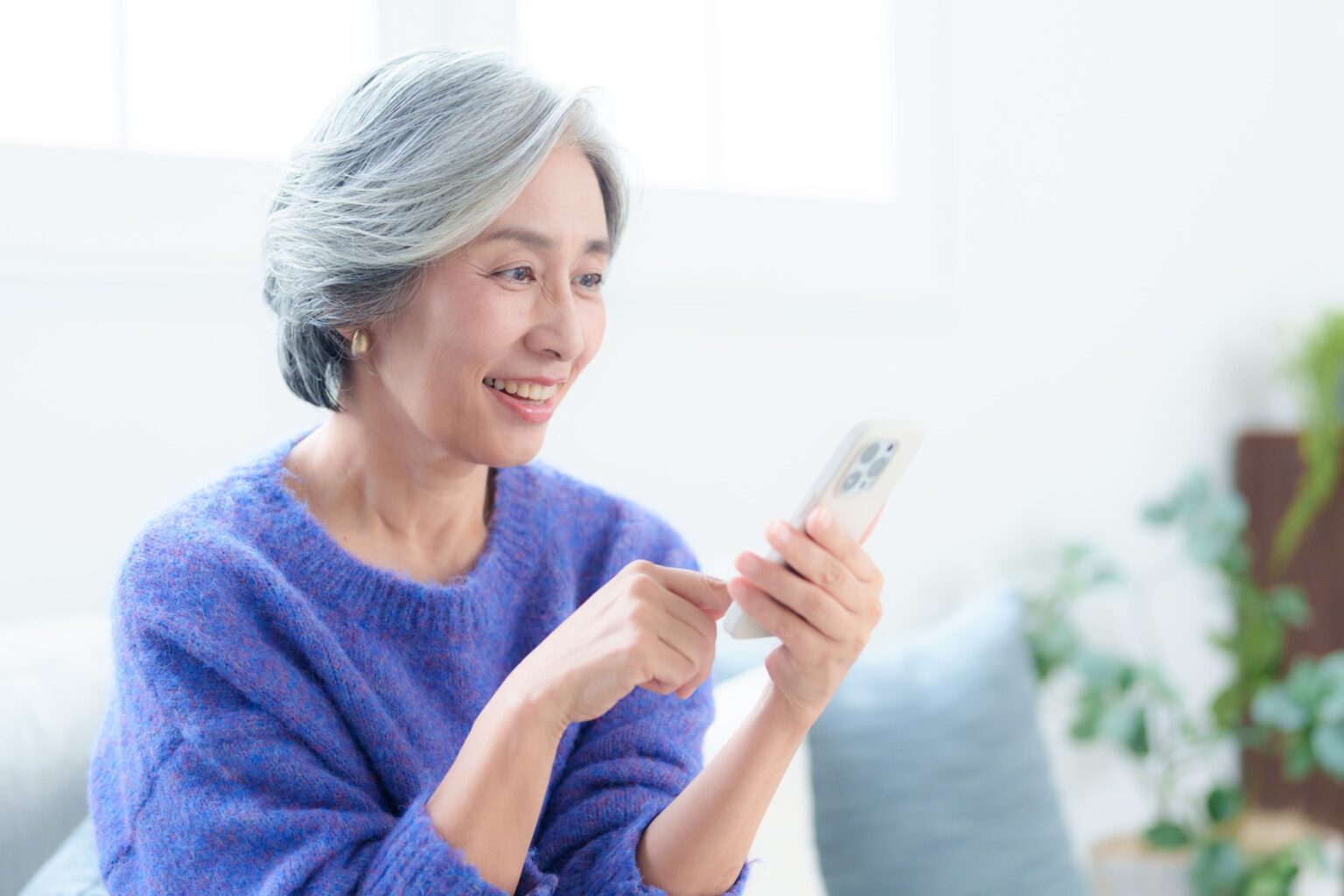 スマートフォンを操作して笑顔を見せる中高年の女性