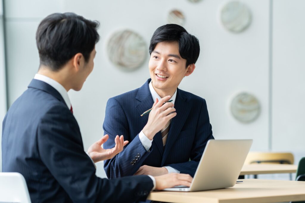 ノートパソコンを前に打ち合わせをする2人のビジネスパーソン