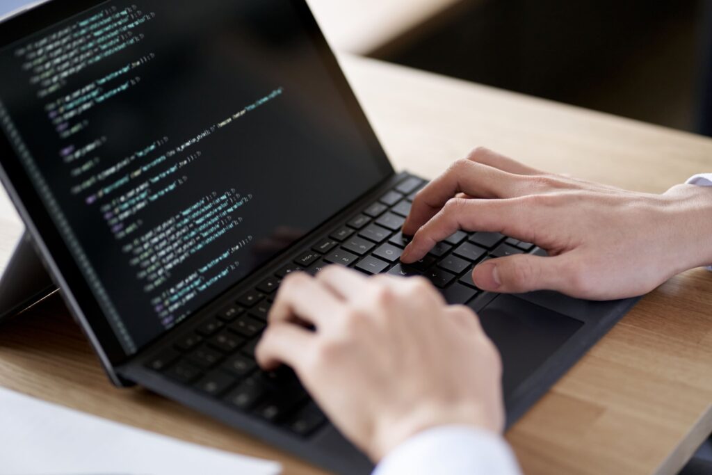 ノートパソコンでプログラムのコードを書く手元