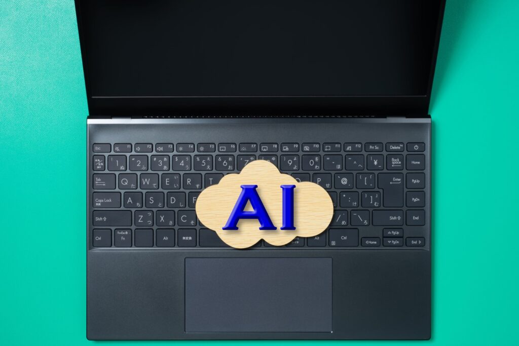 ノートパソコンのキーボードの上に置かれたAIの文字